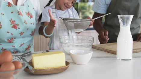 Biracial-girl-with-dark-hair-helps-in-the-kitchen,-giving-a-thumbs-up