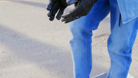 Side-view-of-young-male-skateboarder-standing-on-skateboard-on-country-road-4k