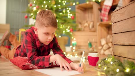 young boy lays on the floor and thinking about his christmas wish list