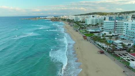 costa de playa de arena en protaras con hoteles de lujo frente a la playa resorts al atardecer, chipre - retiro aéreo