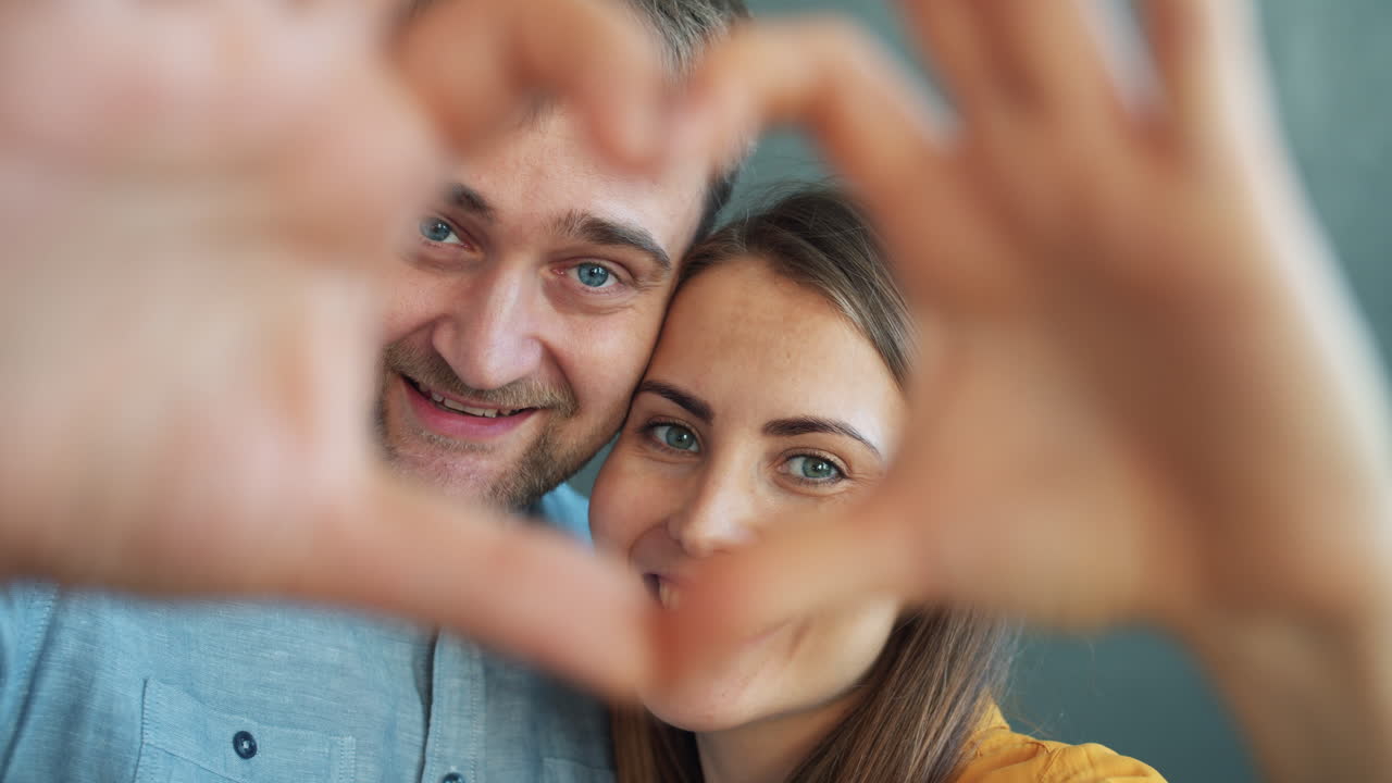 pareja feliz haciendo forma de corazón con las manos