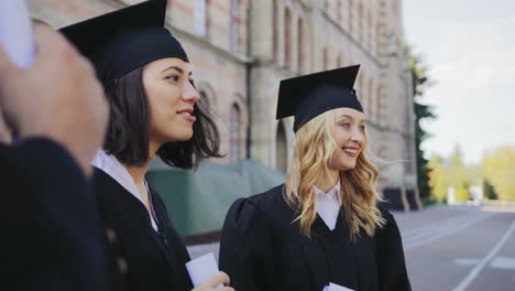 mujer joven contando algo entre sus amigos el día de la graduación