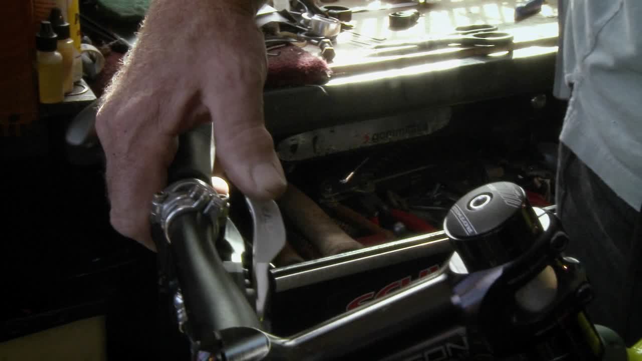 un hombre está reparando una pieza en el manillar de una bicicleta