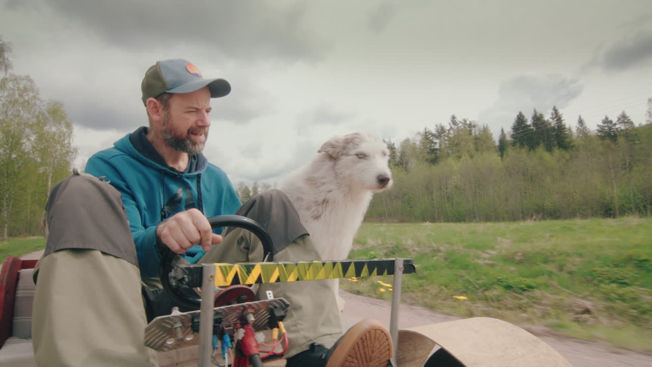 Man and cute husky collie dog drive electric gokart down country road, front POV