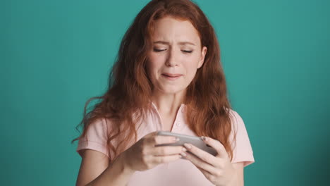 Redheaded girl in front of camera on turquoise background.