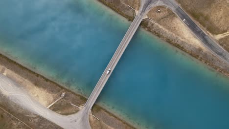 car drives over bridge crossing man-made hydro canal with blue water