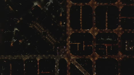 Top-down-panning-footage-of-night-city.-Vehicles-driving-in-streets-and-passing-through-crossroads.-Barcelona,-Spain