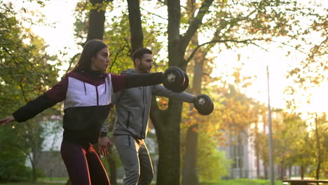 couple exercising with dumbbells in the park