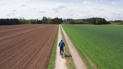 man riding an e-bike on a straight dirt road on a sunny day