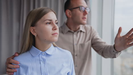 young lady having headache and feels tired. male colleague tries to comfort her and distract her pointing at window.