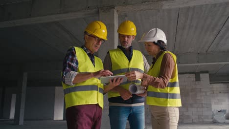 zoom en el video de tres ingenieros caucásicos discutiendo sobre una tableta digital en el sitio de construcción.