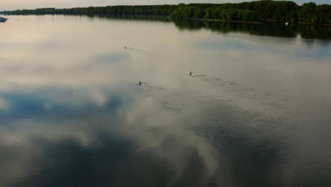 scene of people rowing during beautiful sunset with clouds reflection on calm danube river in vukovar, croatia