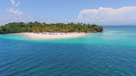 Aerial-orbiting-shot-of-exotic-island-named-cayo-levantado-with-palm-trees-and-sandy-beach-surrounded-by-turquoise-water-at-sunlight