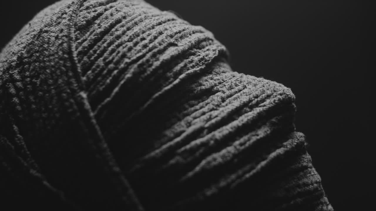 A mummy of a woman on a dark backdrop turns her head