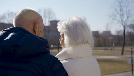 rear view of a senior couple hugging and talking in the park on a winter day