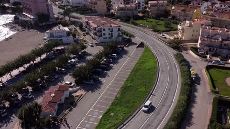 disparo de drones de un coche blanco conduciendo a lo largo de una carretera costera en la costa brava, en cataluña, españa