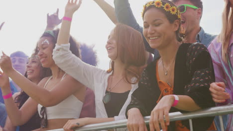 grupo de jóvenes amigos bailando detrás de una barrera en un festival de música al aire libre