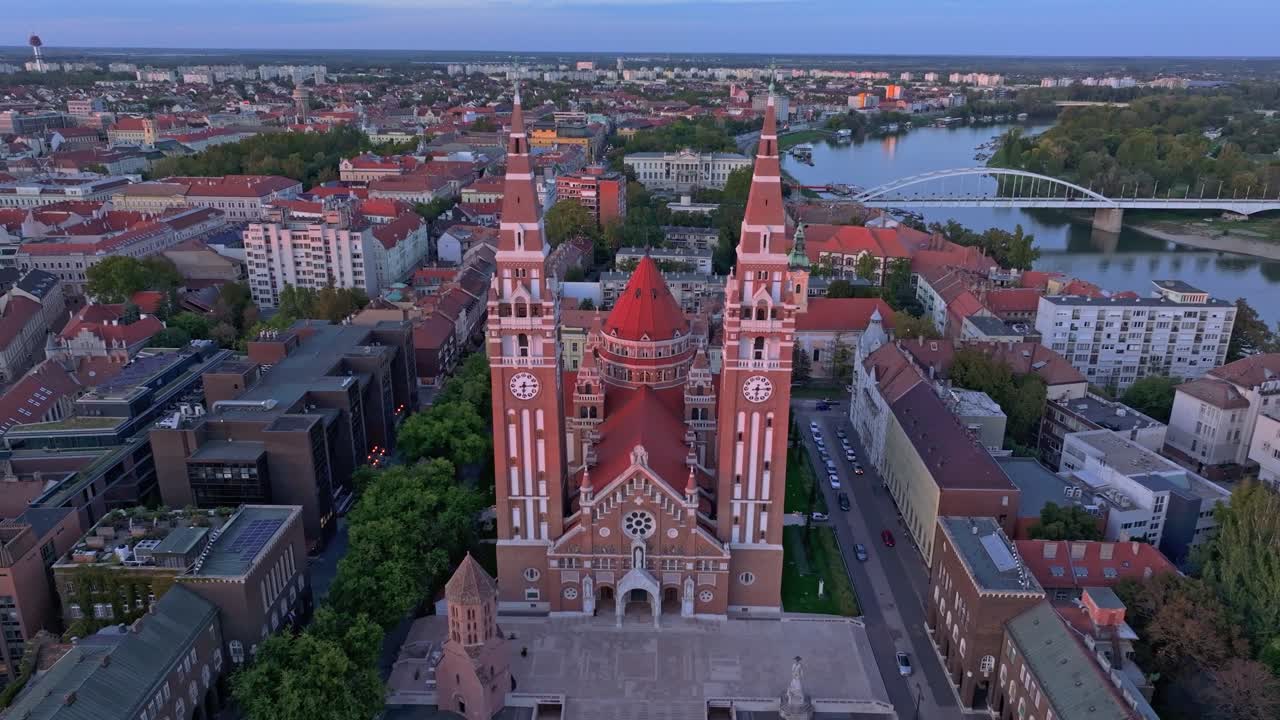 Ripresa aerea del Duomo di Seghedino con lo skyline illuminato d'arancio, Ungheria.