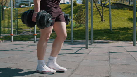 athletic man in sportswear shoes doing exercises with weight, squatting with dumbbells in hands