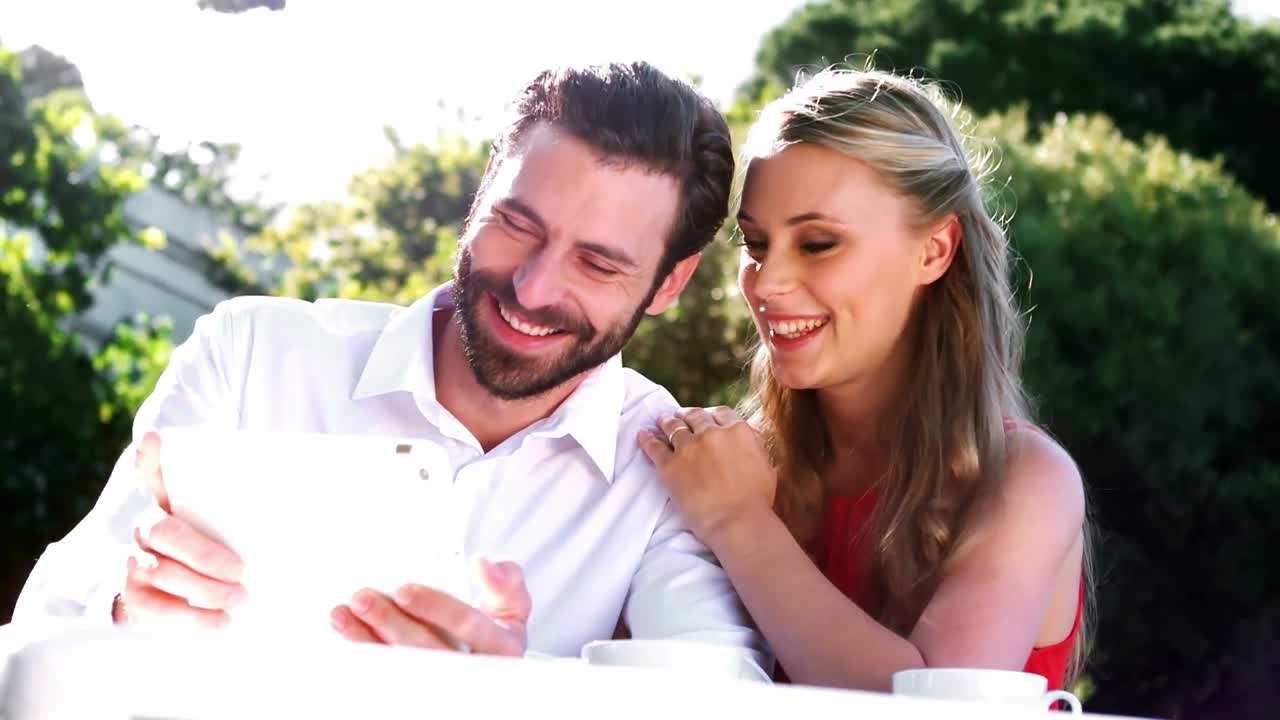una pareja romántica sonriente usando una tableta digital