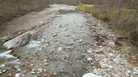 a closeup shot of rocks and pebbles forming a riverbed over which a shallow river runs steadily