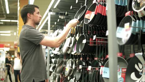 hombre comprando utensilios de cocina en un supermercado