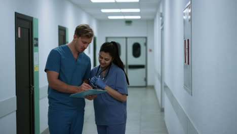 doctor consulting colleague woman in hospital. medical team analysing report.