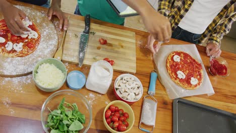 Diverse-male-teenage-friends-cooking-and-preparing-pizza-in-kitchen,-slow-motion