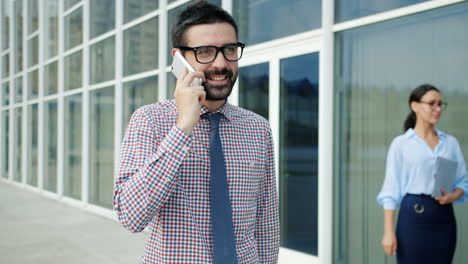 hombre de negocios hablando por teléfono fuera del edificio de oficinas
