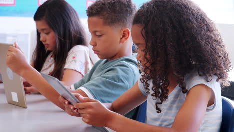 Tres-Alumnos-Usando-Tabletas-En-Una-Lección-En-La-Escuela-Primaria.