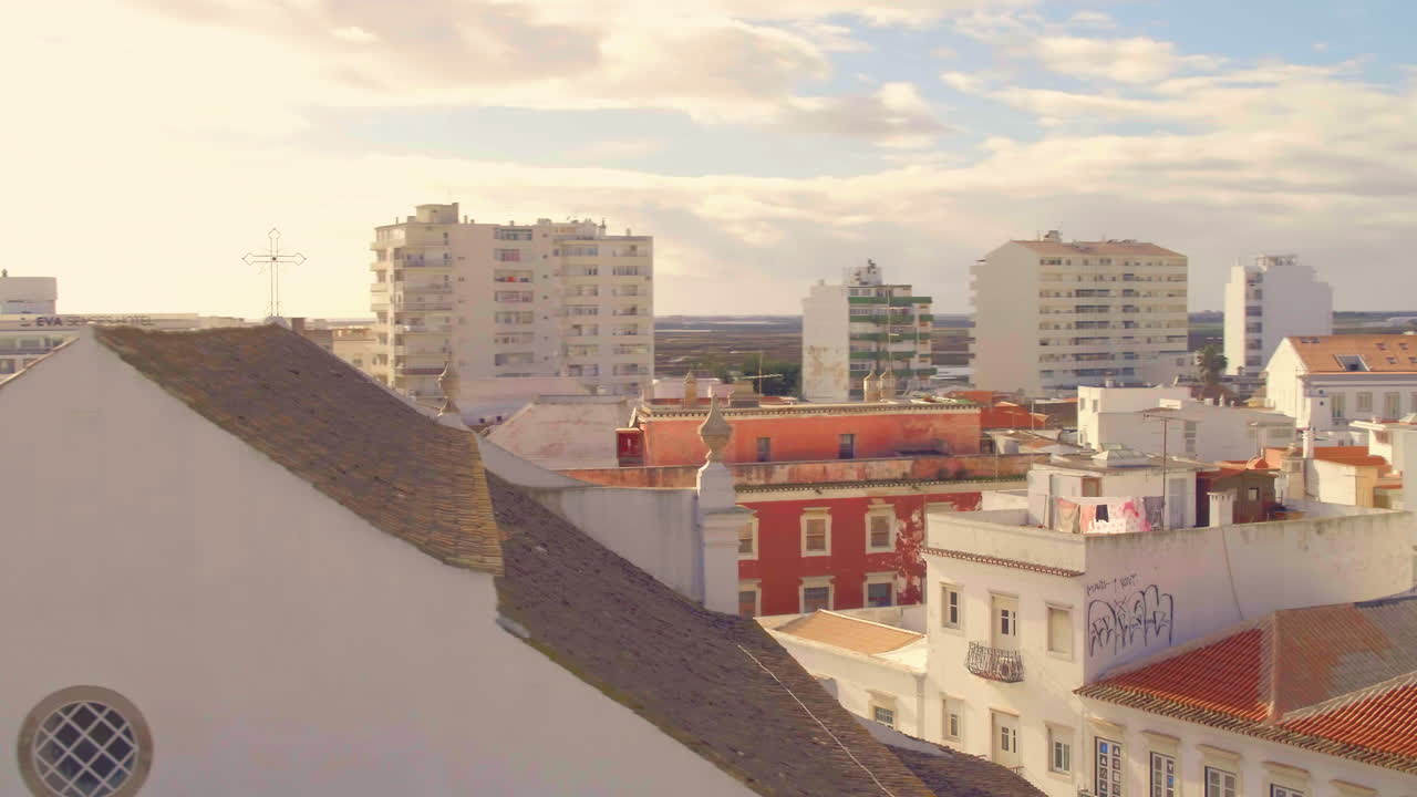Paesaggio urbano di Faro al tramonto con casa storica rossa e vista sulla Ria Formosa