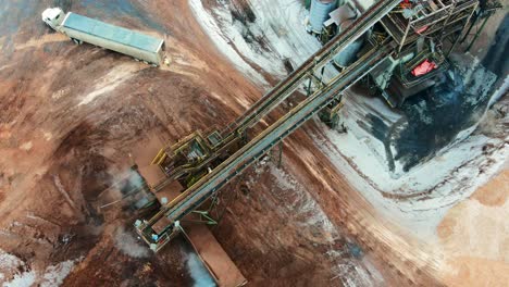 winter waste material management at sawmill with overhead shot of conveyor belt system in action