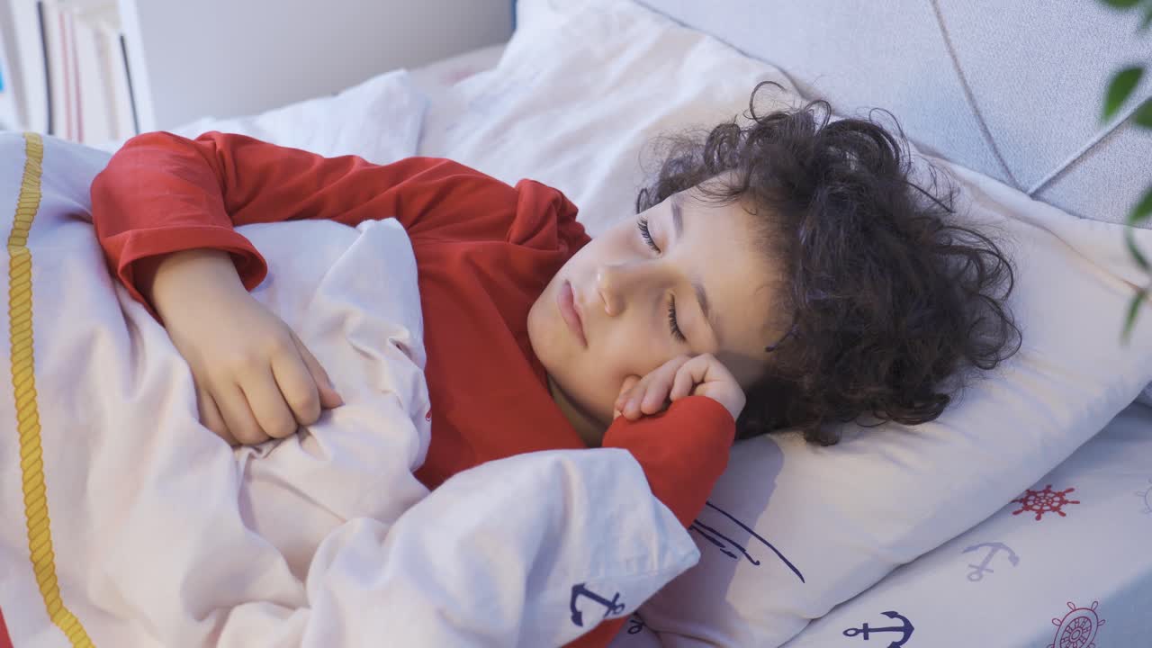 그의 침대에서 달 ⁇ 하게 잠을 자는 소년.