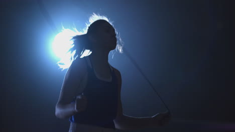 woman boxer jumping on skipping rope in the boxing hall with a ring