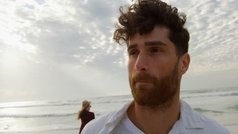 Front-view-of-young-caucasian-man-standing-at-beach-on-a-sunny-day-4k