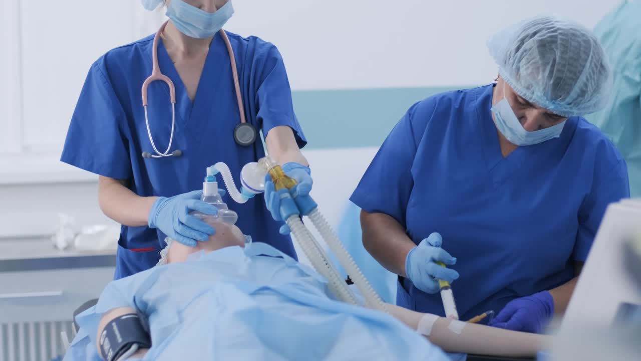 의료 장갑을 입은 마취 의사는 여성 환자를 수술에 준비하고, 환자를 마취에 넣고, 산소 마스크를 조절합니다. 간호사는 정맥 내 마취, 정맥 내 카테터, 수술, 마취를 관리합니다.