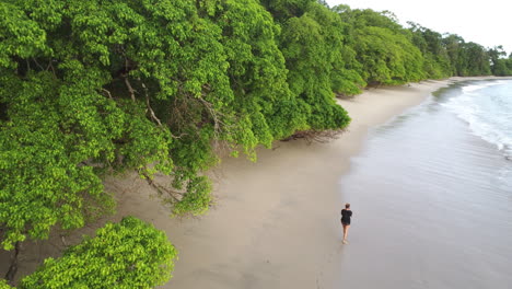 woman walking over tropical beach with incoming waves splashing her
