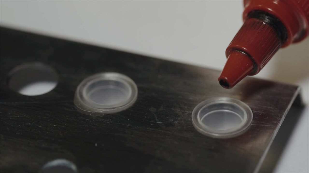 aplicando tinta de tatuaje en una placa de metal