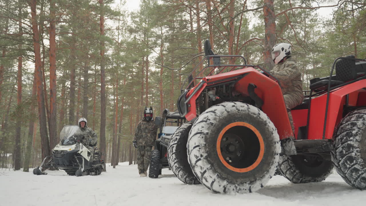 Un ATV rosso sfreccia su un sentiero innevato con un unico pilota. Un pilota mimetizzato accelera su un quad rosso brillante sulla neve compatta, con pneumatici robusti che sollevano la neve. Lo sfondo della pineta e l'effetto mosso trasmettono velocità.