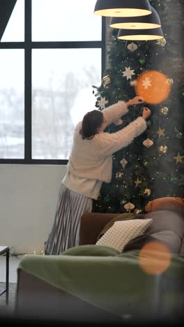 woman decorating a christmas tree in a cozy living room