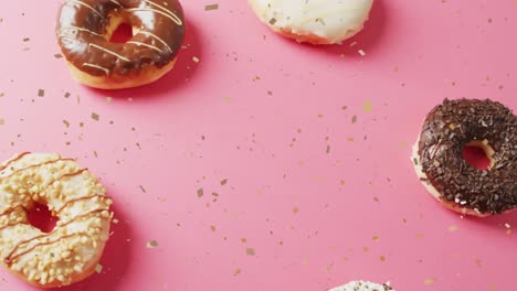 Animation-of-confetti-falling-over-donuts-on-pink-background