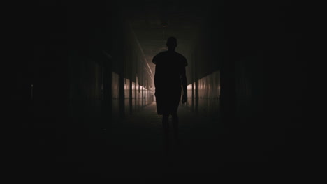 a bald man walks on the empty hospital corridor at night