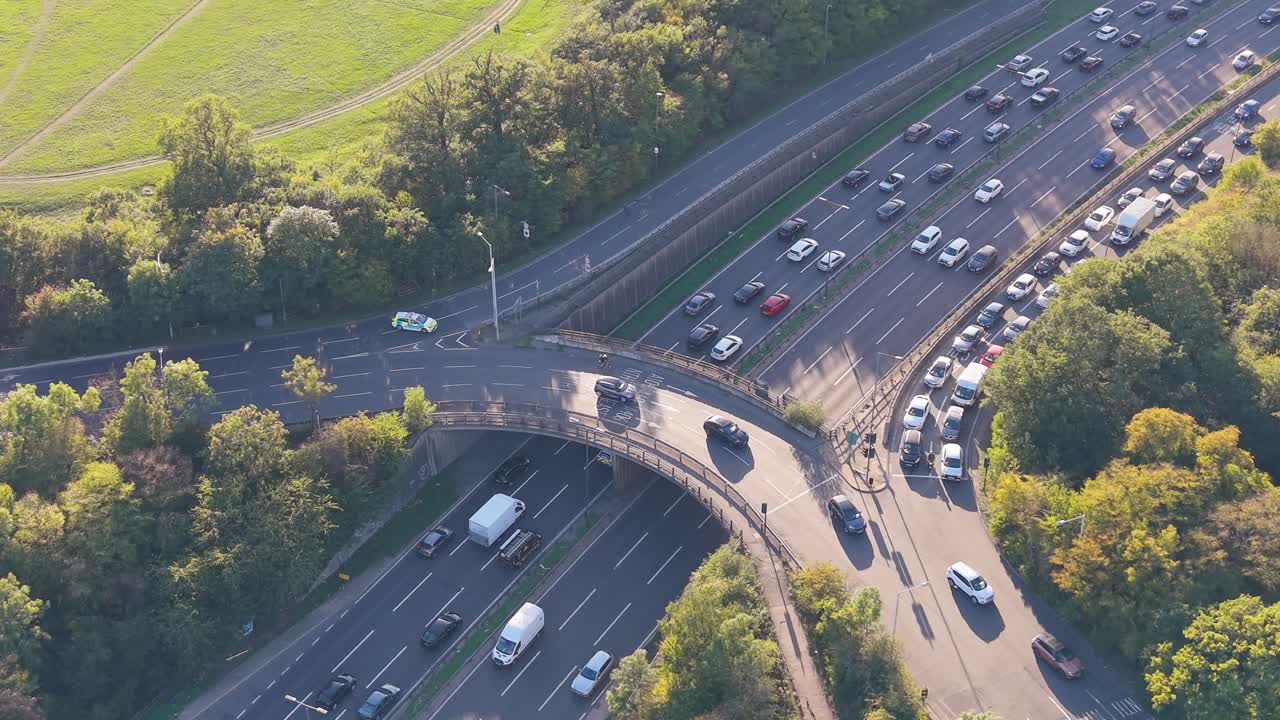 Aerial drone partial orbit over the Waterworks Roundabout, London. Westbound sliproad is blocked by police, causing slow traffic and rubbernecking, while eastbound lanes remain clear and flowing