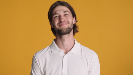 caucasian man waving at camera on yellow background.