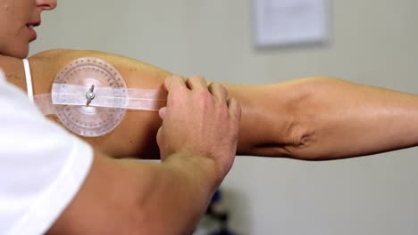 male therapist measuring female patient's back with medical ruler