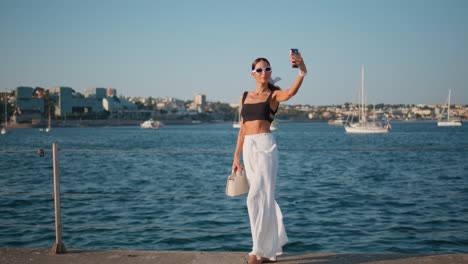 mujer elegante tomando una selfie junto al paseo marítimo