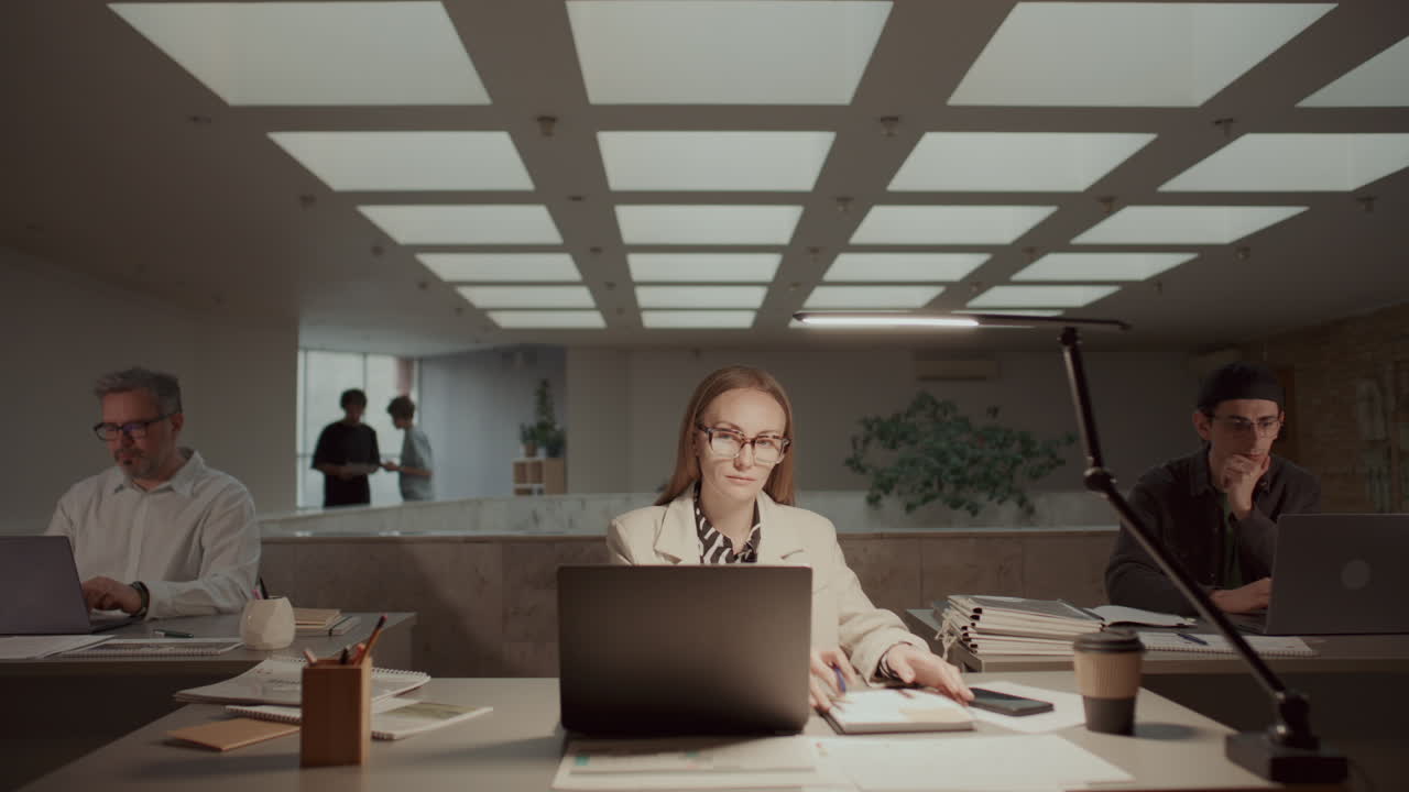 Businesswoman Working on Laptop and Taking Notes in Open Space Office