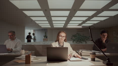 businesswoman working on laptop and taking notes in open space office