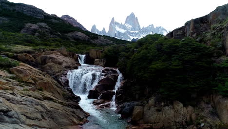 aerial - mount fitz roy behind a waterfall, patagonia, argentina, wide shot