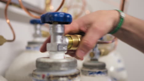 a person's hand disconnecting pipe from gas cylinders from the pipe system by unscrewing the valve - close-up